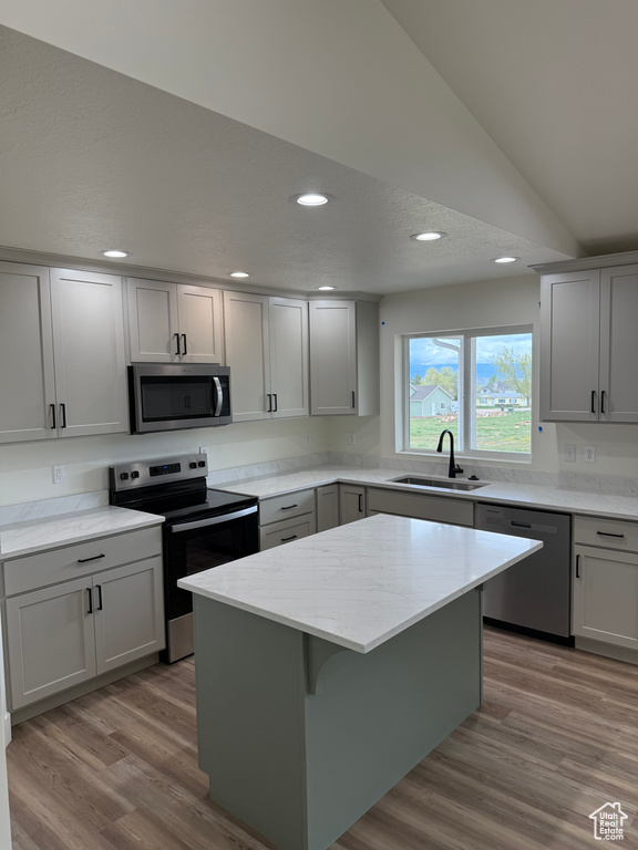 Kitchen featuring appliances with stainless steel finishes, a sink, lofted ceiling, a kitchen island, and recessed lighting