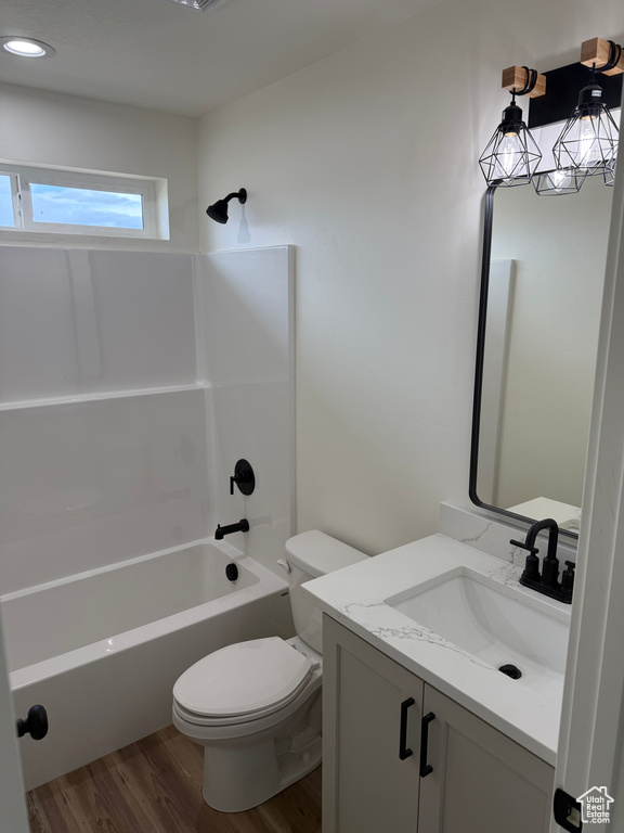Bathroom with wood finished floors, toilet, vanity, and tub / shower combination