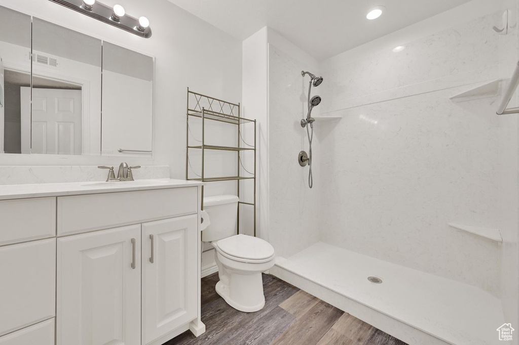 Full bathroom with toilet, wood finished floors, a shower, and vanity