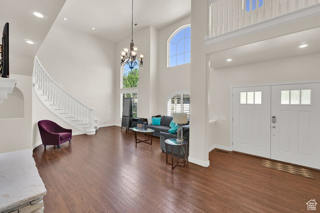 Entryway with a towering ceiling, wood finished floors, stairway, a chandelier, and baseboards