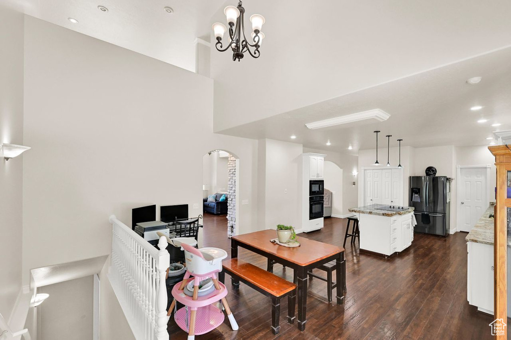 Dining space featuring arched walkways, dark wood finished floors, recessed lighting, a chandelier, and baseboards