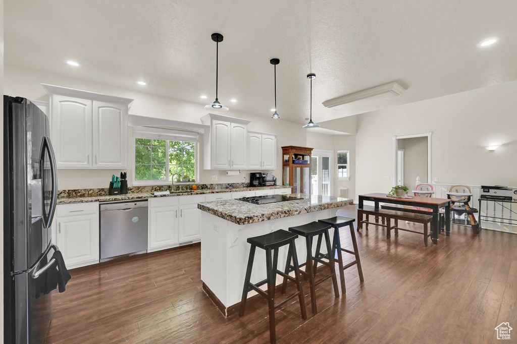 Kitchen featuring black appliances, light stone counters, white cabinetry, dark wood-type flooring, and a kitchen island