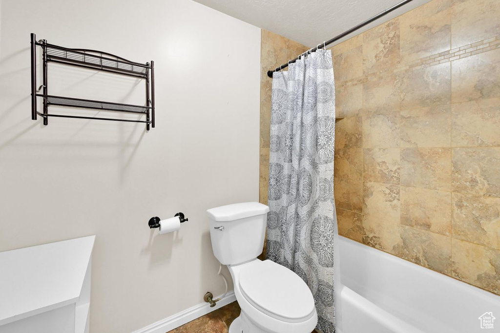 Bathroom with toilet, baseboards, and shower / bath combo