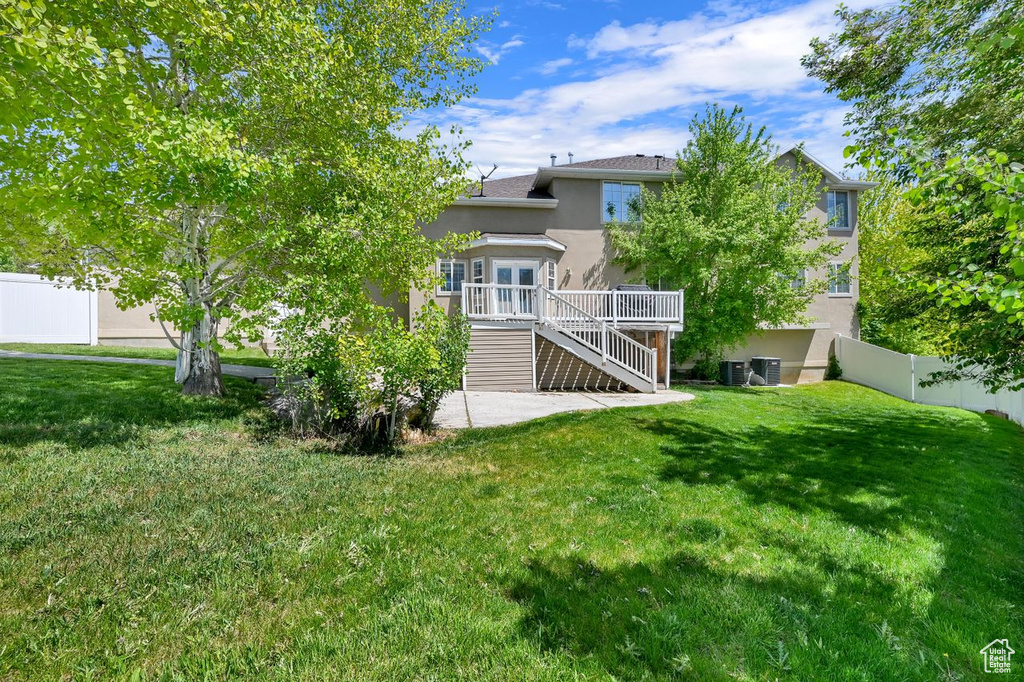 Back of property with stucco siding, stairs, cooling unit, a wooden deck, and a patio area
