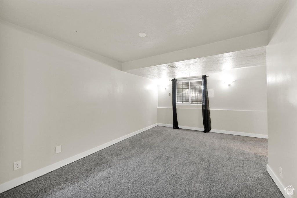 Carpeted spare room featuring baseboards