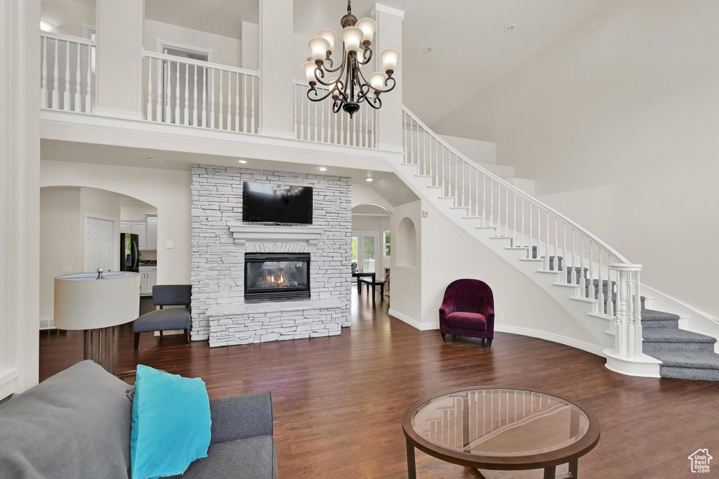 Living room featuring wood finished floors, a towering ceiling, stairs, a fireplace, and baseboards