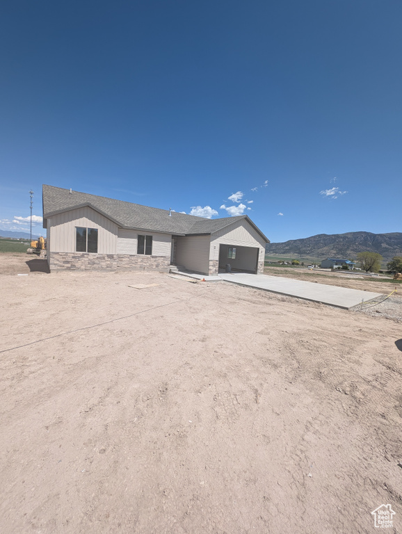 View of front of property with a garage, stone siding, driveway, and a mountain view