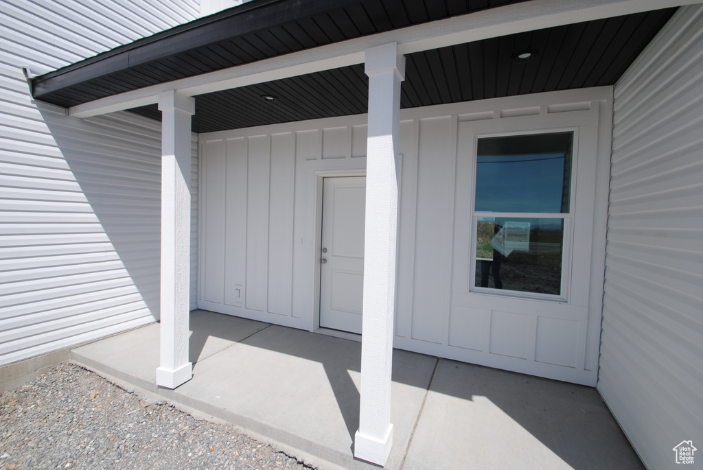 Doorway to property with board and batten siding and a patio area