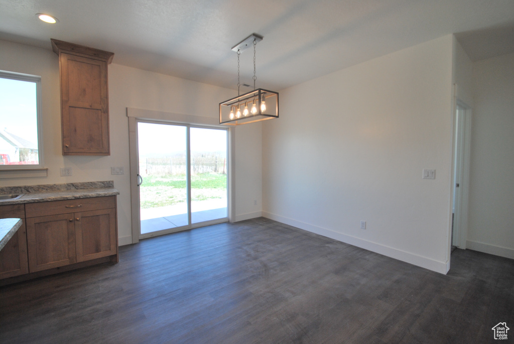 Kitchen featuring dark wood-type flooring, brown cabinetry, baseboards, pendant lighting, and recessed lighting