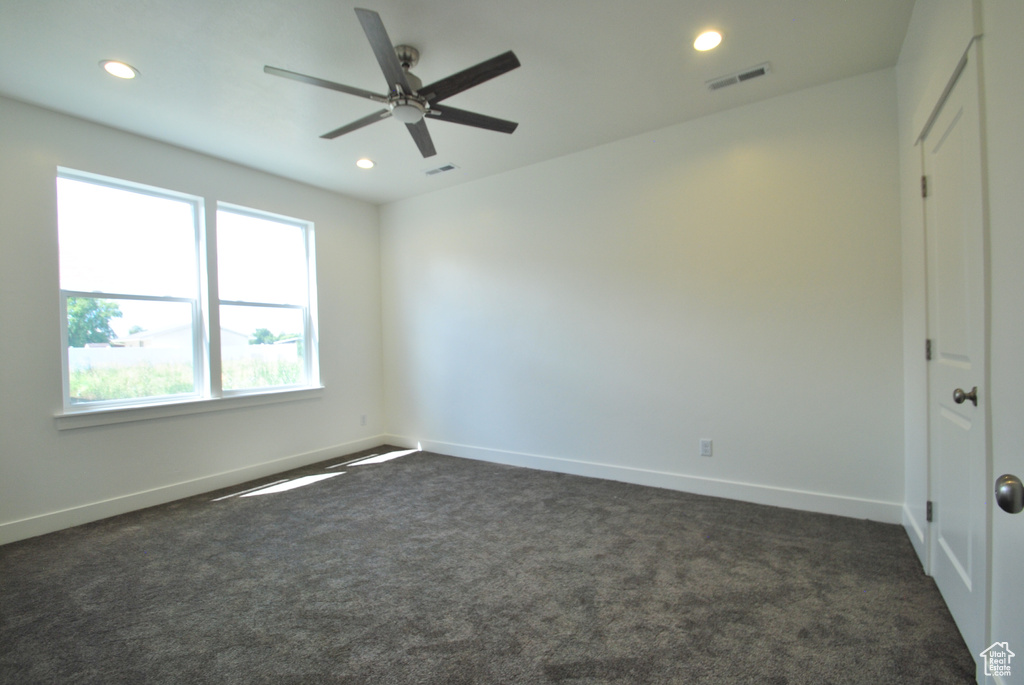Empty room featuring dark colored carpet, recessed lighting, ceiling fan, and baseboards