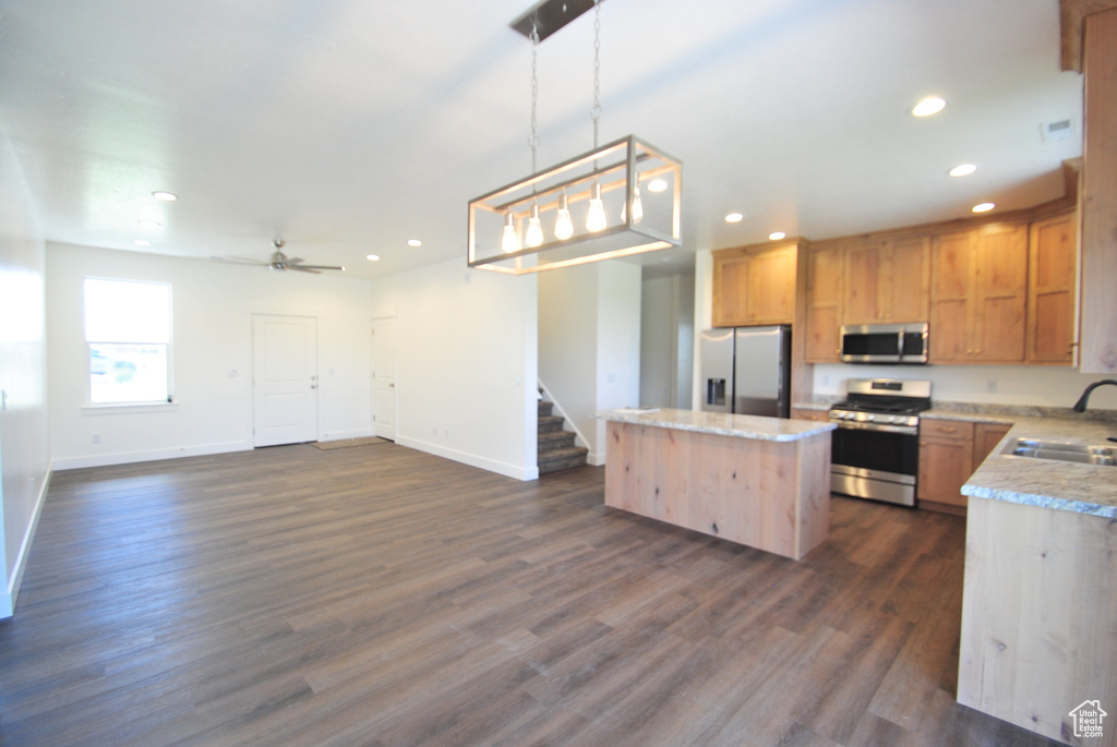 Kitchen with appliances with stainless steel finishes, a kitchen island, recessed lighting, baseboards, and a sink