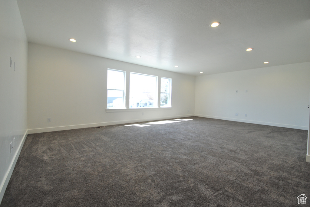Spare room with recessed lighting, baseboards, and dark carpet