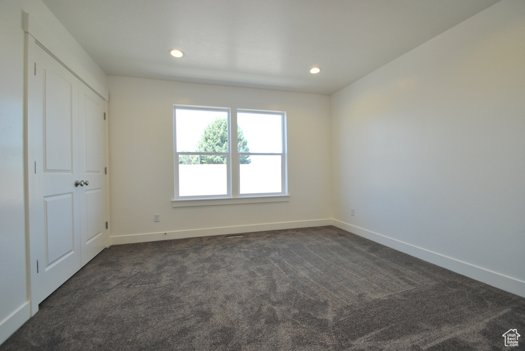 Empty room featuring baseboards, recessed lighting, and dark carpet