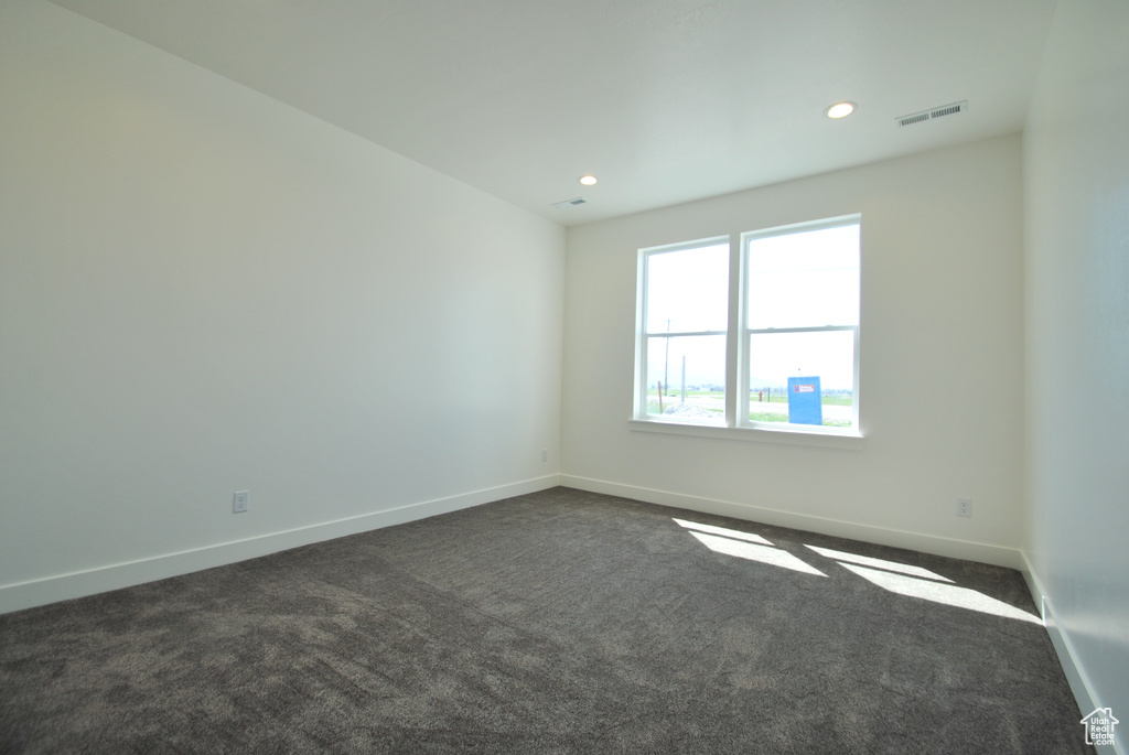 Empty room with dark carpet, baseboards, and recessed lighting