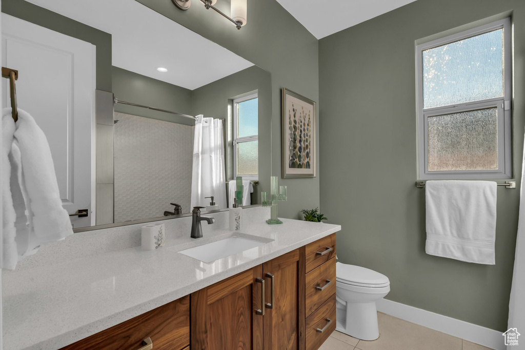 Bathroom featuring a shower with shower curtain, toilet, tile patterned flooring, vanity, and baseboards
