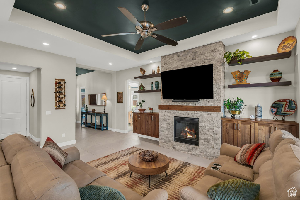 Living room with a tray ceiling, ceiling fan, baseboards, a fireplace, and recessed lighting