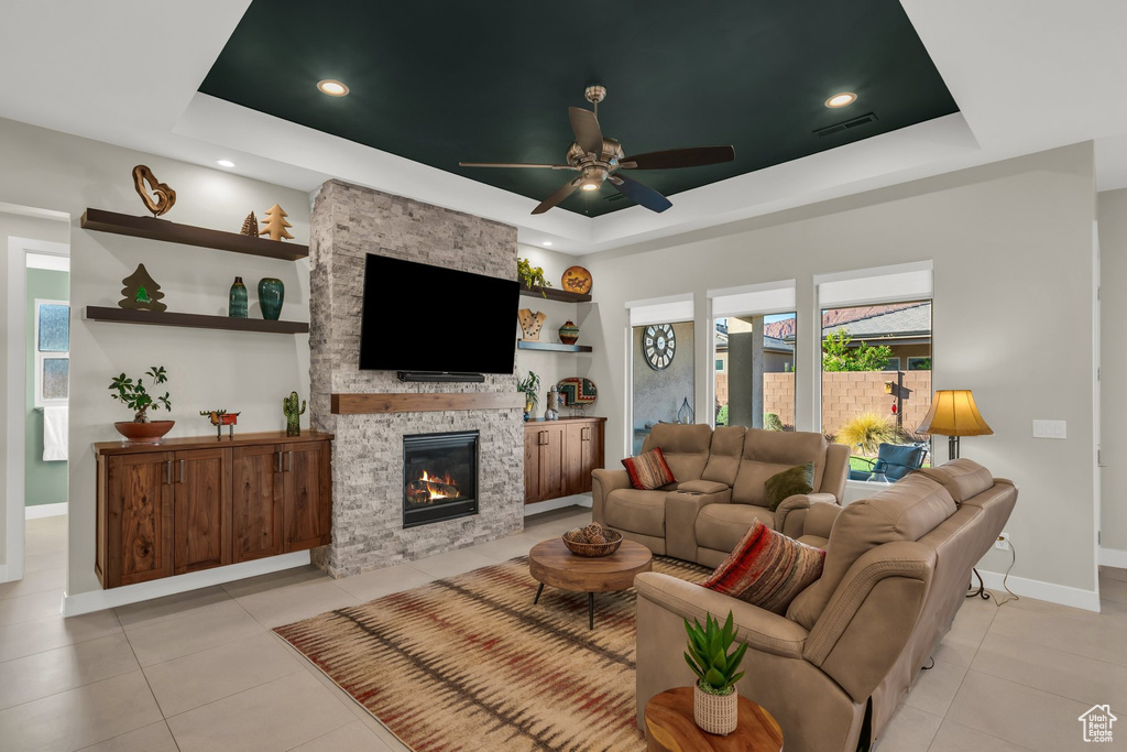 Living area featuring a tray ceiling, baseboards, light tile patterned flooring, a ceiling fan, and recessed lighting