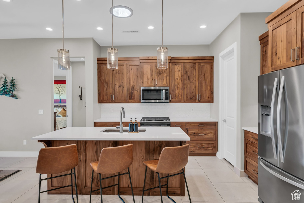 Kitchen with appliances with stainless steel finishes, a sink, brown cabinetry, and recessed lighting