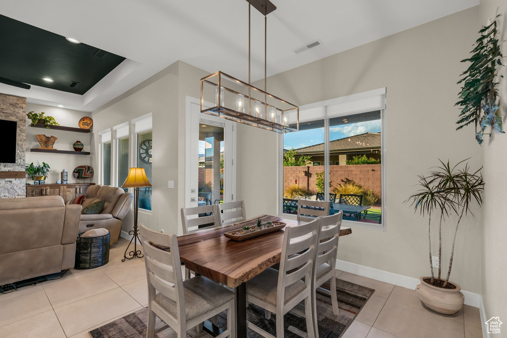 Dining space with light tile patterned flooring, a chandelier, and baseboards