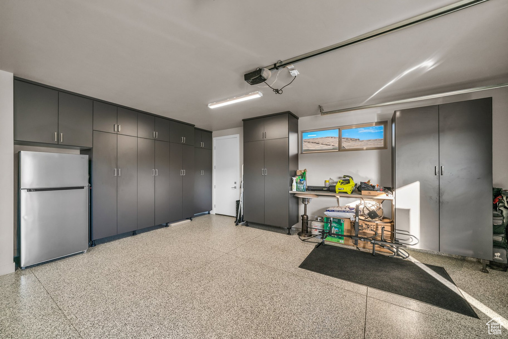Garage featuring freestanding refrigerator and a garage door opener