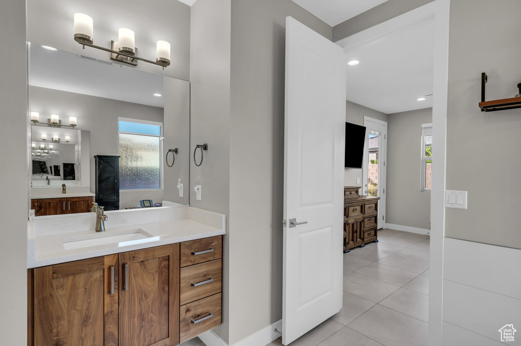 Bathroom featuring baseboards, two vanities, healthy amount of natural light, tile patterned flooring, and recessed lighting