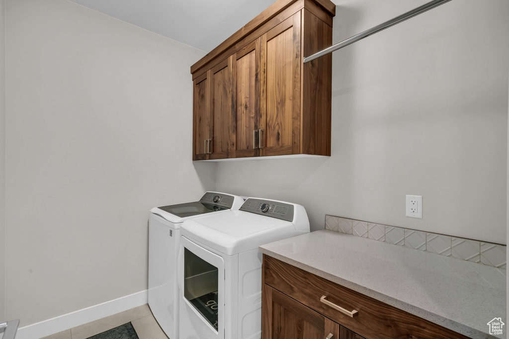 Washroom featuring independent washer and dryer, cabinet space, baseboards, and light tile patterned floors