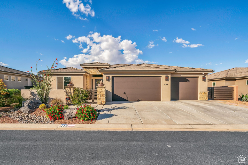 Prairie-style home with an attached garage, stucco siding, driveway, and a tiled roof