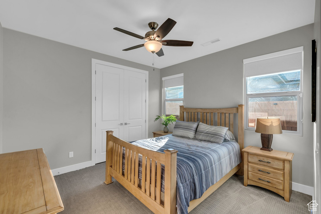 Carpeted bedroom with a closet, baseboards, and a ceiling fan