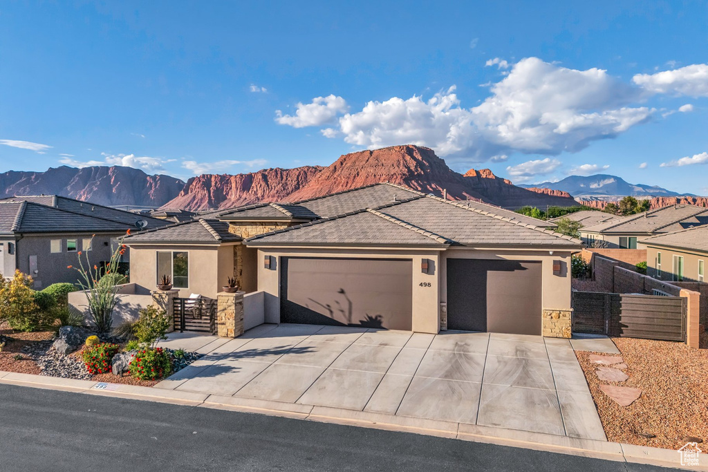 View of front of property featuring an attached garage, stucco siding, a mountain view, and fence
