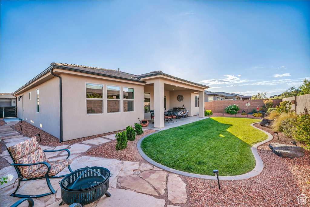 Rear view of house featuring a patio area, stucco siding, and a tiled roof