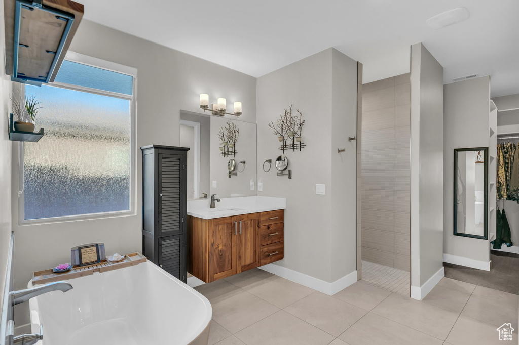 Full bathroom with a freestanding tub, vanity, baseboards, a tile shower, and tile patterned flooring