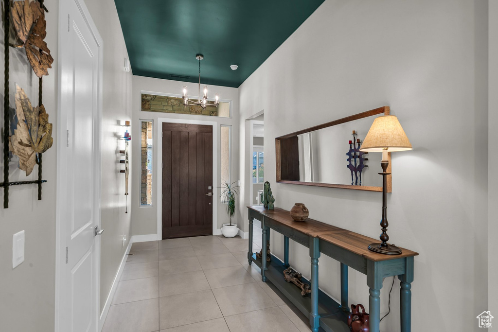 Tiled entrance foyer featuring a chandelier and baseboards