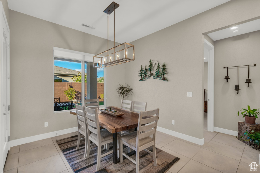Dining area featuring a chandelier, baseboards, and light tile patterned flooring