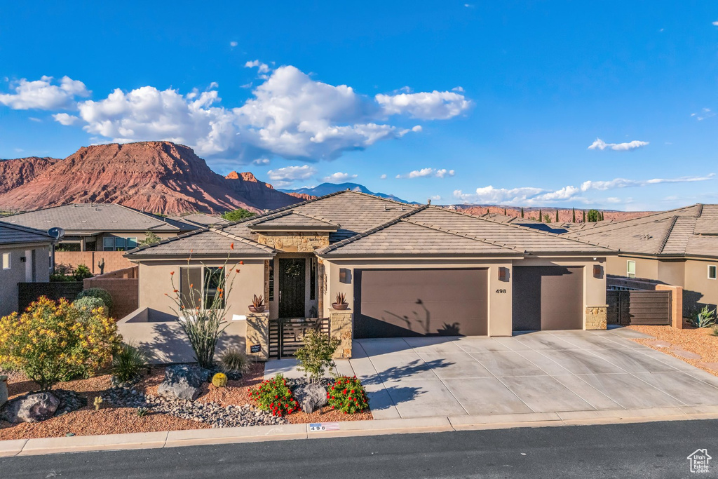 View of front of home with stucco siding, a garage, stone siding, and fence
