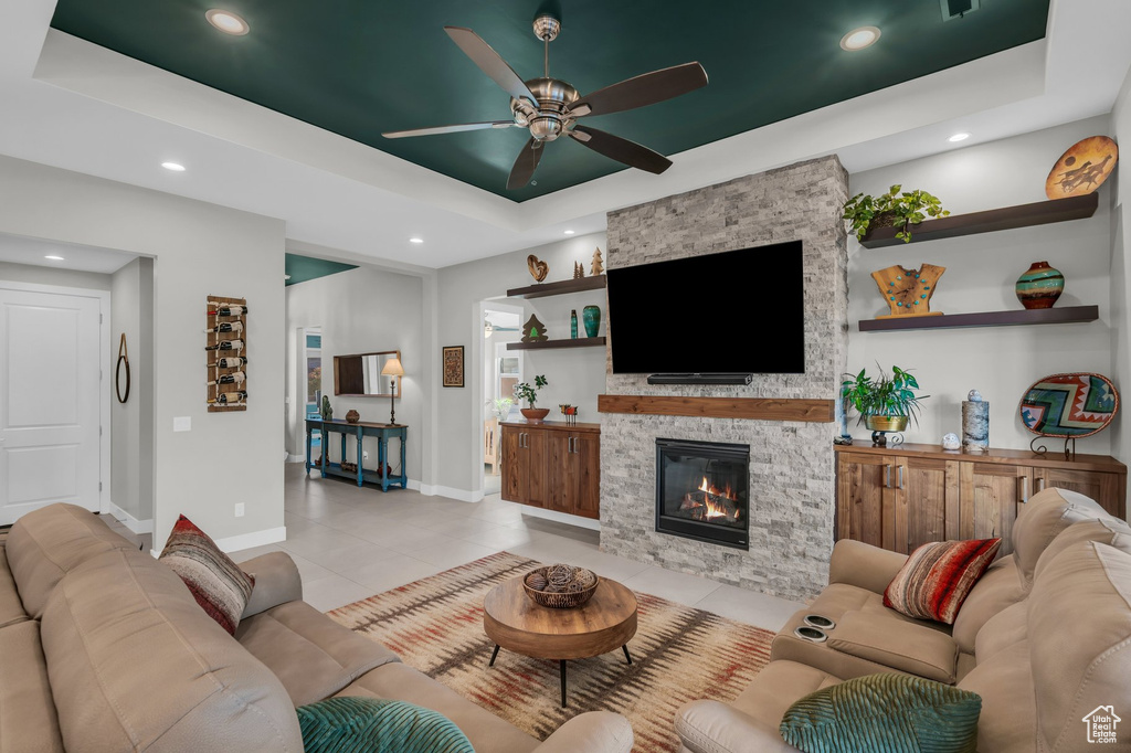 Living area featuring a raised ceiling, ceiling fan, baseboards, a fireplace, and recessed lighting