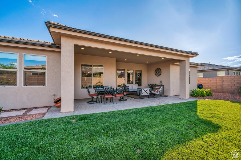 Back of property featuring stucco siding, a patio area, and an outdoor hangout area