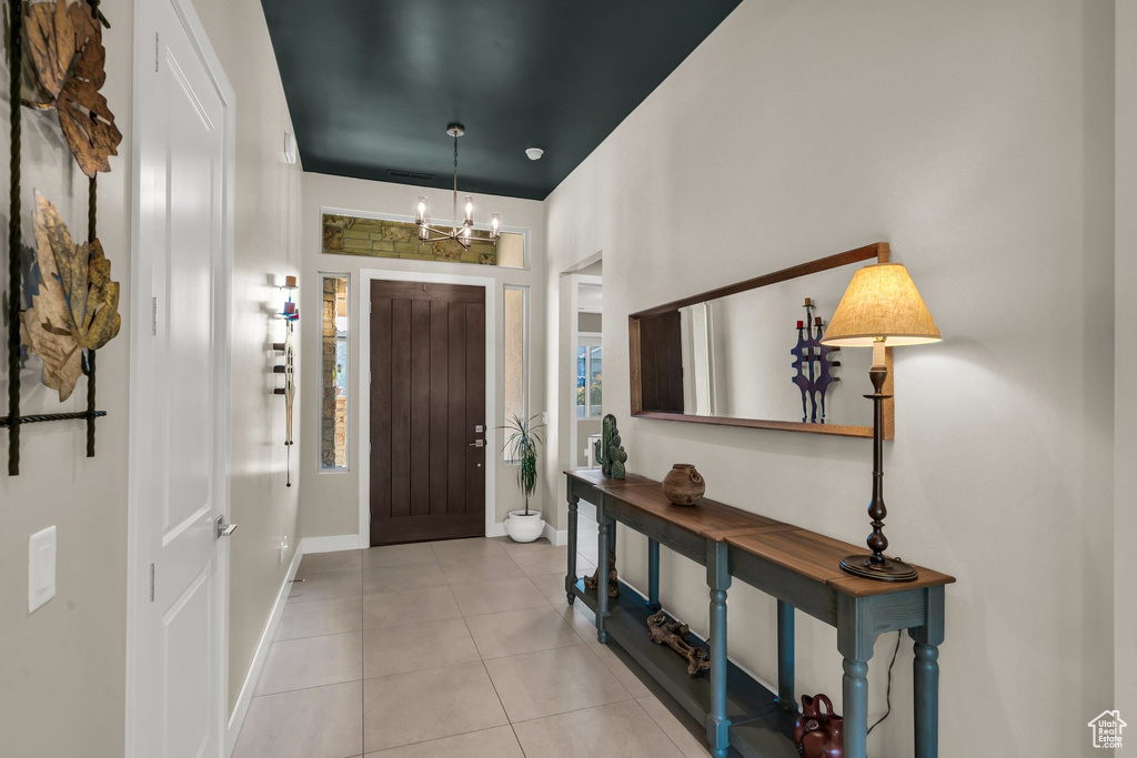 Tiled entrance foyer featuring a chandelier and baseboards