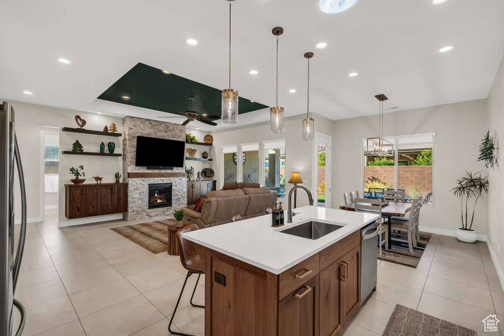 Kitchen featuring a sink, dishwasher, light tile patterned floors, freestanding refrigerator, and a ceiling fan