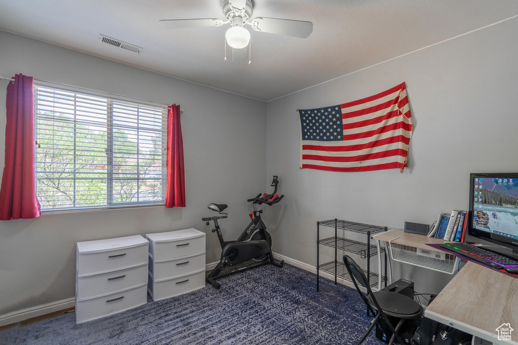 Carpeted office space with ceiling fan and baseboards