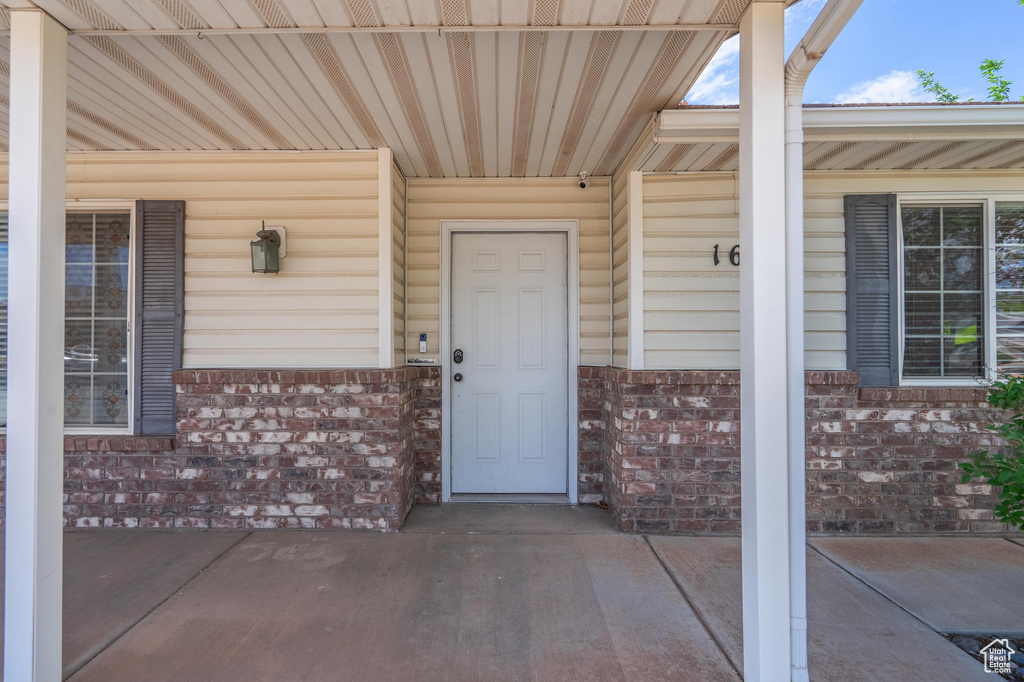Entrance to property featuring brick siding and covered porch