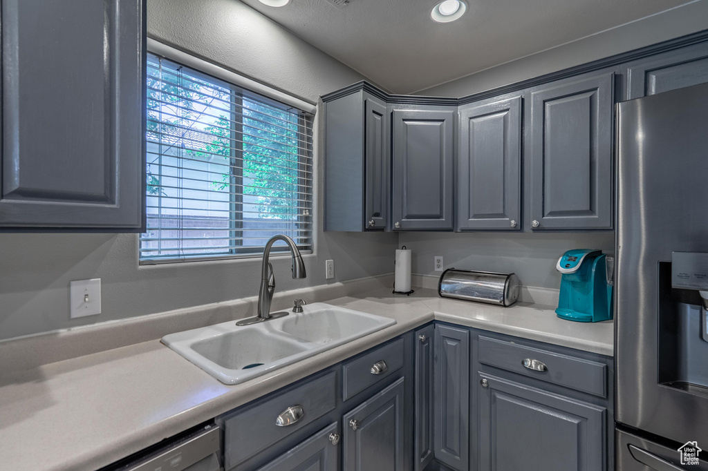 Kitchen featuring stainless steel fridge with ice dispenser, a sink, gray cabinets, light countertops, and dishwasher