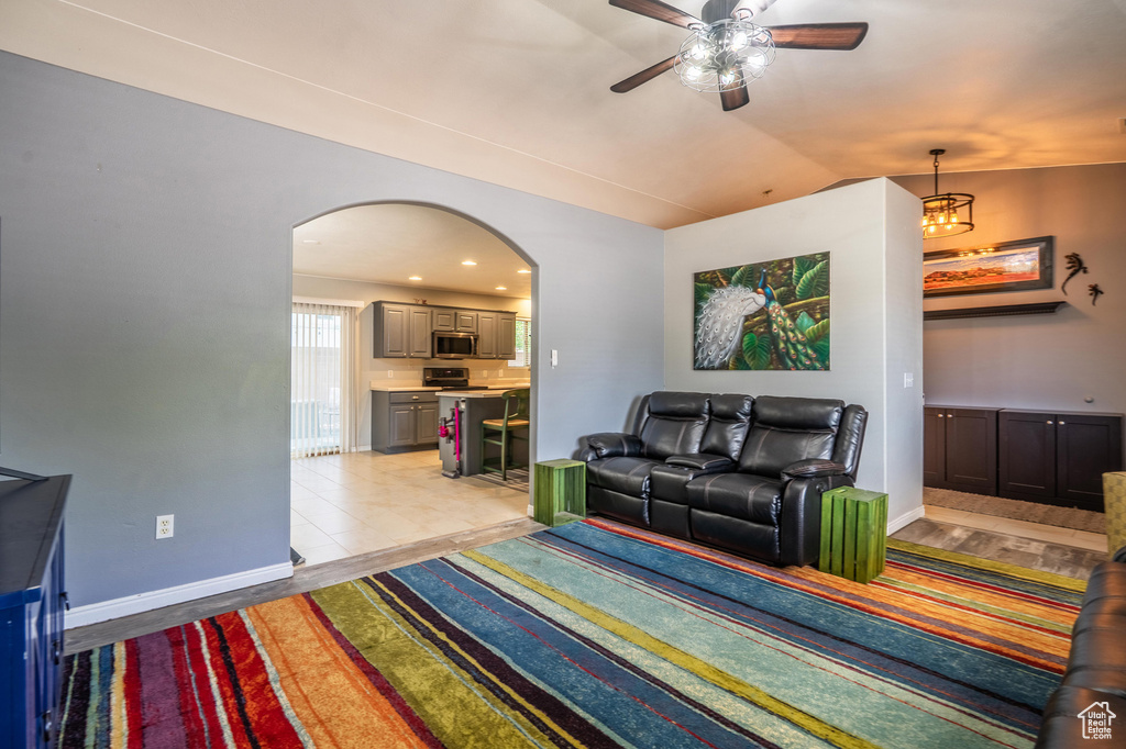 Living area with arched walkways, ceiling fan, lofted ceiling, and baseboards