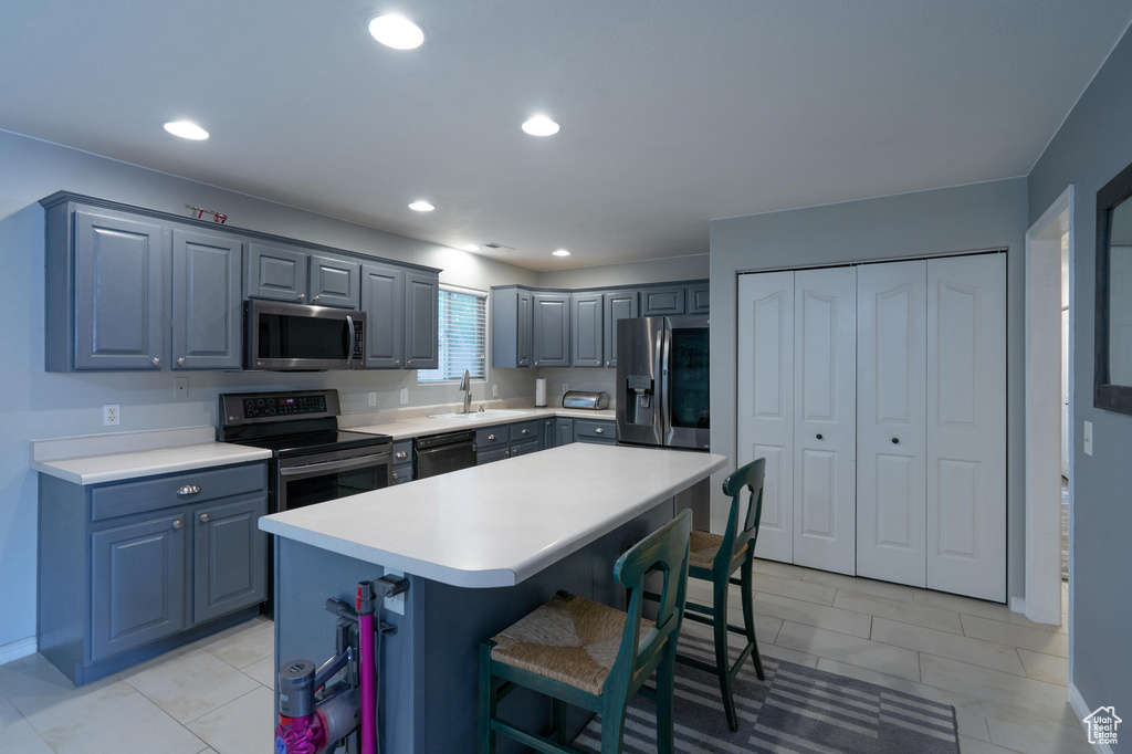 Kitchen featuring appliances with stainless steel finishes, a breakfast bar area, light countertops, a kitchen island, and recessed lighting