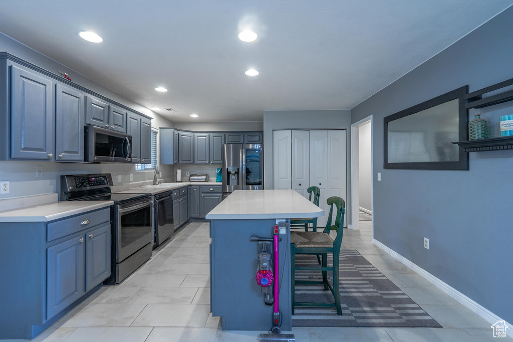 Kitchen featuring stainless steel appliances, a kitchen breakfast bar, light countertops, a kitchen island, and recessed lighting