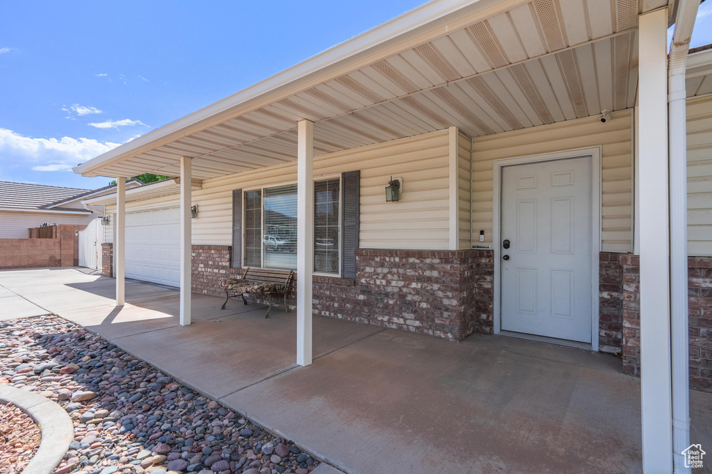 View of patio / terrace with concrete driveway, a garage, and a porch