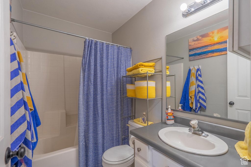 Full bathroom featuring toilet, vanity, and shower / bath combination with curtain
