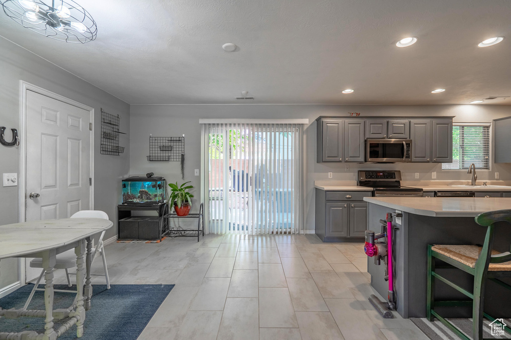 Kitchen featuring gray cabinetry, stainless steel appliances, light countertops, a sink, and recessed lighting