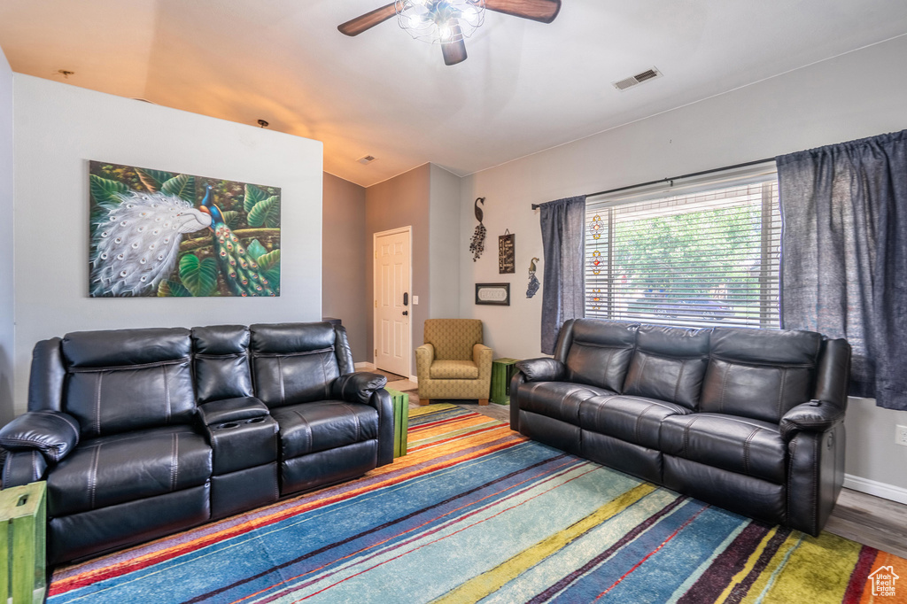 Living room with a ceiling fan, wood finished floors, and baseboards