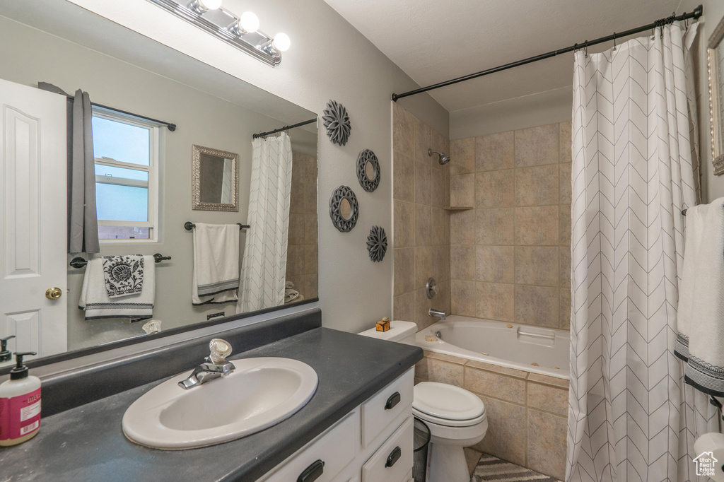 Bathroom featuring tiled shower / bath, vanity, and toilet