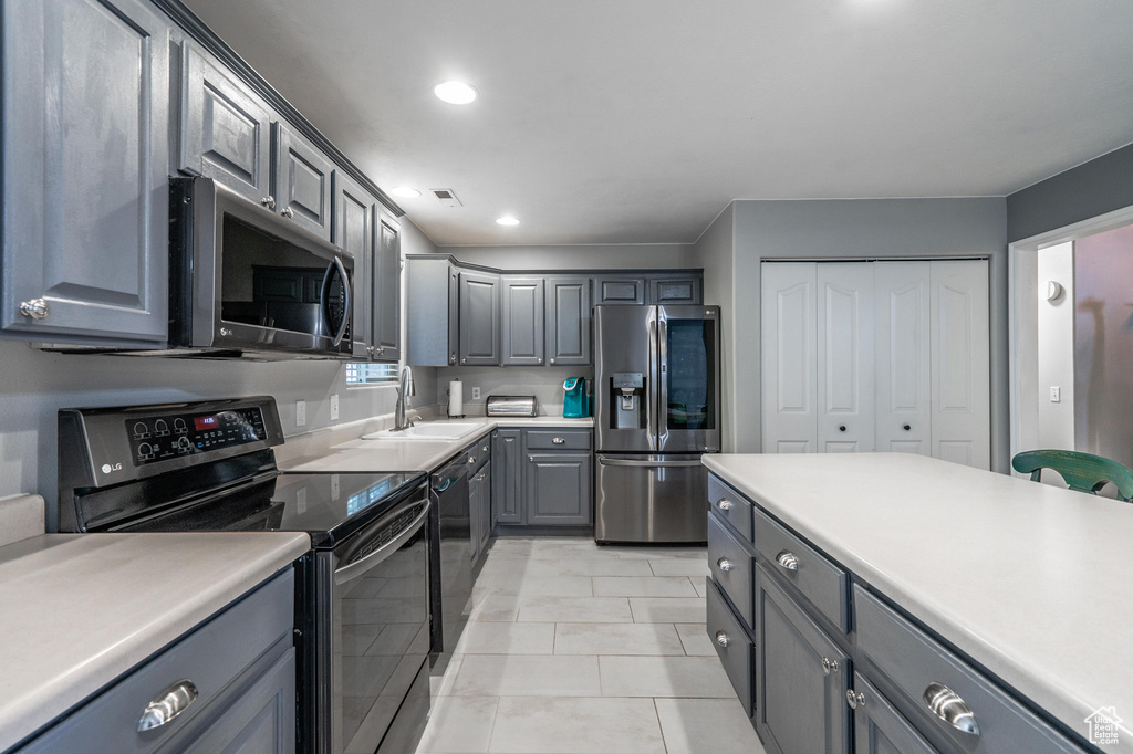 Kitchen featuring stainless steel appliances, gray cabinetry, a sink, recessed lighting, and light countertops